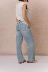 Jean wide leg de tiro medio-alto en denim azul medio con lavado desgastado. Presenta diseño de cinco bolsillos, cierre con botón y cremallera, y pierna amplia de caída recta.