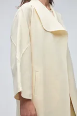 Tapado de largo medio abierto con cuello, confeccionado en lana fina sin teñir con detalles de terminación envivados en los bordes y mangas tres cuartos.