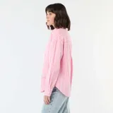 Camisa de manga larga confeccionada en popelina de algodón, con diseño de rayas verticales en tonos rosa y blanco. Presenta cuello clásico, cierre frontal con botones y corte holgado.