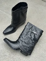 Bota corta de cuero negro con caña arrugada, puntera fina y hebilla decorativa en el lateral.