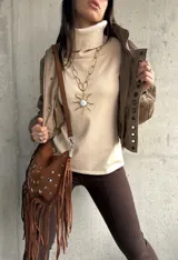 Polera de tejido de punto color beige, con cuello alto, mangas largas y aberturas laterales en el ruedo.