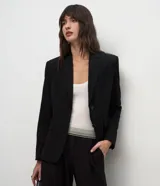 Blazer de corte sastre color negro, con cuello de solapas, cierre frontal de dos botones y forro interno. Presenta una estructura recta y refinada.