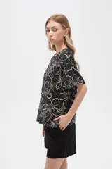 Blusa holgada de viscosa con estampado floral en tonos verde militar y blanco. Presenta cuello a la base, abertura frontal con botones y mangas cortas.