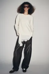 Camiseta color crudo de cuello redondo y manga larga, con detalle de aplicación de tejido lencero asimétrico a tono en el ruedo.