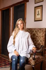 Camisa blanca de algodón con cuello mao, corte amplio, mangas largas abullonadas con puños abotonados y detalle de canesú con pliegues en el pecho.
