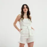 Mono corto color crudo con breteles finos, cinturón con hebilla metálica y volados en el ruedo del short.