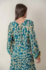 Vestido largo de viscosa con estampado abstracto en tonos azul petróleo y beige. Tiene mangas largas anchas terminadas en puño fruncido, corte en la cintura y bajo con volado y guarda.