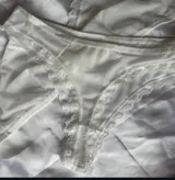 Conjunto de lencería de dos piezas color blanco, confeccionado en tela suave y semitransparente con detalles de encaje en los bordes. Incluye un bralette triangular sin aro ni relleno, con breteles regulables y una bombacha vedetina a juego.
