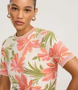Blusa de calce entallado confeccionada en viscolycra con estampa floral en tonos rosados y verdes sobre fondo crema. Presenta cuello redondo y terminaciones de mangas cortas en tejido de punto acanalado de color rosado.