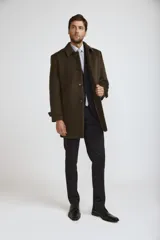 Abrigo tipo carcoat de paño en color verde oliva, con cierre frontal de botones, cuello clásico y bolsillos laterales. Presenta un diseño estructurado y elegante, ideal para climas fríos.