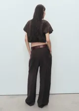 Blusa crop de color marrón, con cuello redondo y mangas cortas abullonadas con diseño estilo globo. Presenta un ajuste elástico en la cintura.