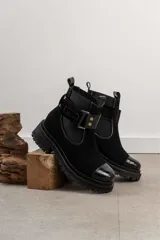 Bota tipo Chelsea de cuero marrón con suela track negra de goma. Presenta paneles elásticos laterales y una costura reforzada en la puntera. Incluye una correa de cuero desmontable con hebilla metálica.