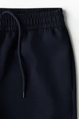 Short de felpa interlock color negro, de corte relajado a la rodilla, con cintura elástica con cordón ajustable oculto y bolsillos laterales.