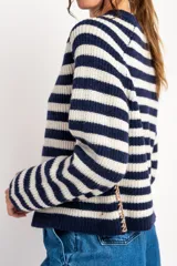 Sweater de lana con rayas horizontales en tonos rojo, rosa, beige y marrón. Presenta costuras decorativas en los laterales y puños en color violeta.