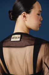 Trench largo de mujer confeccionado en tul transparente, con cuello camisero, mangas largas y frente abierto. Presenta una caída fluida y ligera, ideal para superponer sobre otras prendas.