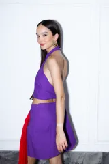 Falda violeta de lino, corte mini con diseño cruzado y lazo lateral rojo.