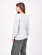 Buzo de tejido de punto color marrón oscuro, con cuello en V y detalles calados horizontales a lo largo del cuerpo y mangas.