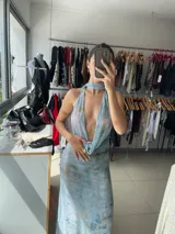 Vestido largo de fiesta con estampado abstracto en tonos celeste y dorado. Tiene escote halter pronunciado y espalda descubierta.