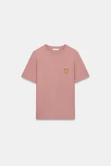Camiseta de algodón con efecto lavado, cuello redondo y manga corta. Presenta un bolsillo pequeño en el pecho con un detalle de fornitura metálica dorada.