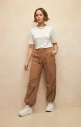 Pantalón babucha color marrón claro, tipo parachute de nylon, con cordones ajustables en la cintura y en las terminaciones de ambas piernas.