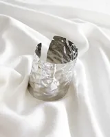 Pulsera rígida plateada con textura irregular.