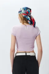 Top corto de manga corta, color negro con efecto desgastado o acid wash, cuello redondo y costuras verticales que definen la silueta.