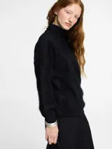 Sweater negro de tejido fino con textura peluche y cuello alto estilo tortuga. Modelo de corte holgado.