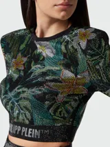 Top corto de manga larga con hombreras y estampado floral de hojas y flores en tonos verdes, amarillos y blancos. Banda elástica con logo de la marca en el bajo.