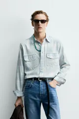 Camisa de algodón con efecto lavado, diseño a cuadros en tonos celestes y beige, cuello solapa, manga larga con puños abotonados y bolsillos frontales con solapa.