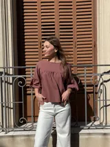 Blusa color chocolate de diseño holgado, con cuello redondo, frunce frontal y mangas abullonadas con puños ajustados.