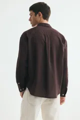 Camisa de manga larga color marrón, con cuello inglés, cierre frontal de botones, bolsillo en el pecho y bajo redondeado. Confeccionada en mezcla de algodón y lino.