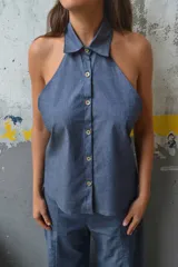 Top azul de corte halter, sin mangas, con cuello camisero y cierre frontal de botones coloridos.