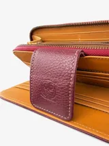 Billetera tipo clutch o cartera de mano, color vino tinto, con textura de cuero cocodrilo (crocco). Presenta un cierre de solapa con broche y costuras en contraste color claro. Incluye una correa de muñeca desmontable.
