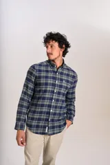 Camisa de manga larga confeccionada en tejido de franela con estampado de cuadros en tonos azul marino y verde. Presenta cuello abotonado, cierre frontal con botones y un bolsillo en el pecho con el logo bordado de la marca.