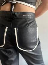 Pantalón de cuero negro con textura de piel de cocodrilo y rayas blancas laterales.