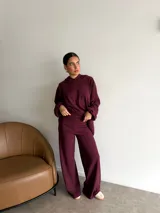 Conjunto de dos piezas compuesto por un buzo con capucha de corte holgado y mangas largas, y un pantalón de corte recto y tiro alto. Ambas prendas son de color marrón liso.