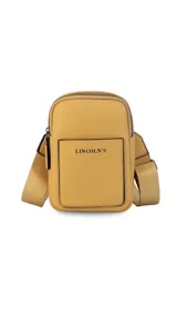 Bandolera pequeña de diseño compacto en color mostaza, confeccionada en material sintético con textura granulada. Presenta un bolsillo frontal con el logo de la marca impreso, cierre superior y correa ancha ajustable y desmontable.