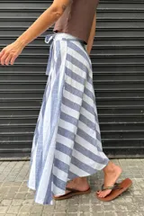 Falda larga confeccionada en 100% algodón con estampado de rayas en azul y blanco. Presenta un diseño cruzado con lazo ajustable en la cintura y caída fluida.