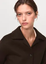 Chaqueta de corte recto confeccionada en mezcla de lana, con cuello camisero, cierre frontal de botones y dos bolsillos de solapa en el frente.