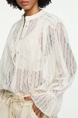 Blusa oversize blanca de encaje calado semitransparente, con cuello mao, cierre frontal de botones, mangas largas abullonadas con puños fruncidos y aberturas laterales en el ruedo.