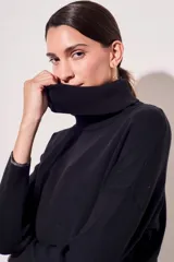 Sweater negro de cuello alto con tajos laterales y detalle de línea plateada en puños y ruedo.