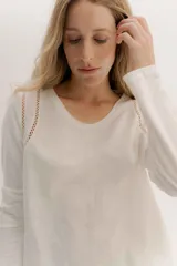 Remera blanca de manga larga con escote a la base. La parte delantera es de algodón y la espalda de remería para mayor elasticidad. Las mangas combinan ambas telas y presenta un detalle de doble entredos en la sisa delantera.