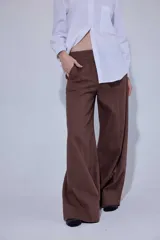 Pantalón de tiro medio y corte ancho, confeccionado en una mezcla de lino y algodón. Presenta costuras verticales frontales, bolsillos laterales y traseros con detalles de remaches.