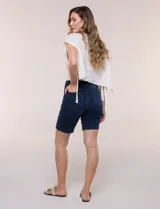 Bermuda de jean azul oscuro con calce ajustado y tecnología push up. Presenta cintura con presillas, cierre frontal con botón metálico, diseño clásico de cinco bolsillos y largo por encima de la rodilla con dobladillo en el ruedo.