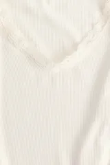 Top ajustado en punto acanalado color blanco, con mangas largas y escote en V ribeteado con encaje.