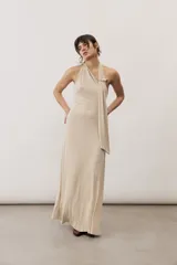 Vestido largo negro de corte al cuerpo con cuello halter y detalle de hebilla metálica dorada en el hombro con tira drapeada.