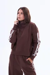 Buzo de felpa color marrón con medio cierre frontal, cuello alto y mangas largas con dos franjas blancas laterales.