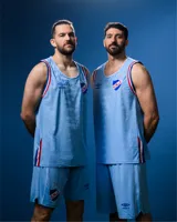 Camiseta de básquet Umbro de edición especial del Club Nacional de Football, color celeste con detalles en azul, blanco y rojo en el cuello y las sisas. Presenta el logo de Umbro y el escudo del club bordados en el pecho.