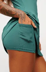 Vestido deportivo negro sin mangas, con escote en V y logo estampado en el pecho. Falda corta con short interno y bolsillos laterales. Incluye protección UV50+.