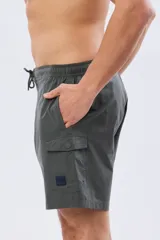 Short de baño cargo color negro, de diseño liso con bolsillos laterales y bolsillos utilitarios con solapa y botón en las piernas. Cuenta con cintura elástica ajustable mediante cordón.
